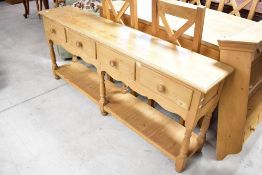 A modern natural pine dresser base, having four drawers and under shelf with turned supports,