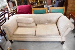 An Edwardian tub chair in the Howard style, with later upholstery and a similar Chesterfield 'drop