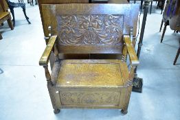 A traditional oak monks bench having green man style decoration to underside of top, width approx.
