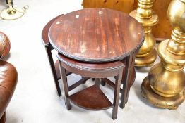 An early 20th Century mahogany nest of table comprising circular table with 'quarter' tables under