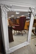 A modern wall mirror having white foliate frame, approx. 115 x 82cm
