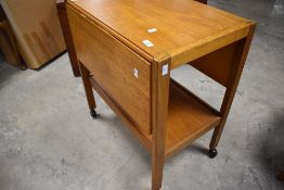 A vintage teak tea trolley with drop flaps and undertier