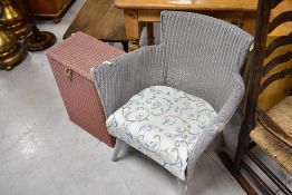 A Lloyd loom tub chair and linen basket , in grey and pink respectively