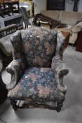 A traditional wing back armchair having floral upholstery and shaped support