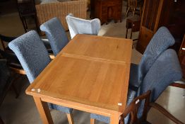 A modern golden oak extending dining table and set of four blue upholstered dining chairs, table
