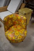 A vintage tub chair having vibrant floral vinyl upholstery and dansette style legs