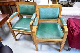 A pair of early 20th Century municipal style carver chairs having golden oak frames and green