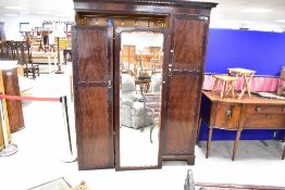 An early 20th Century mahogany triple wardrobe having mirrored central door