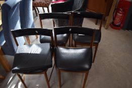 A set of four vintage McIntosh dining chairs having low black vinyl back and seat ('Tuckaway' Design