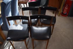 A set of four vintage McIntosh dining chairs having low black vinyl back and seat ('Tuckaway' Design