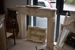 A French style white painted plaster fire surround and a pearlescent shelf unit