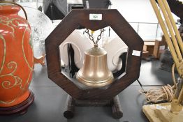 A vintage brass bell with an octagonal hard wood table stand, unmarked, 34cm in height, condition