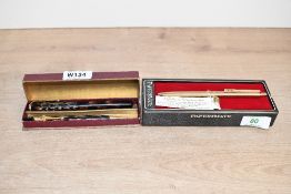 A boxed button fill fountain pen and pencil set in gold and brown marble with a dagger shaped clip