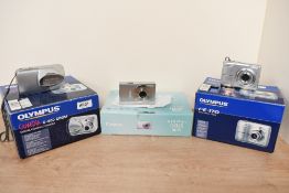Three boxed digital cameras. An Olympus Camedia C-360 Zoom with disc and booklet, an Olympus FE-