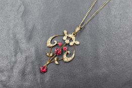An Edwardian yellow metal pendant stamped 9ct having red paste stones within a split pearl decorated