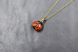An enamelled seed pendant in the form of a ladybird on a 16'yellow metal chain stamped 9ct, 1.5g