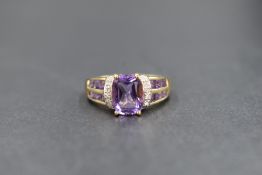 A 9ct gold QVC amethyst and diamond set dress ring, the central cushion cut amethyst flanked by