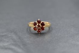 A 9ct gold red paste set daisy cluster ring, the central round cut paste in a six paste surround,