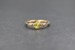 A 9ct gold peridot and diamond ring having a central peridot in a six claw mount flanked by two