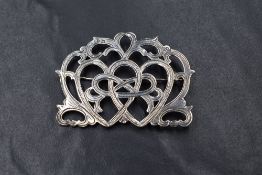 A Victorian silver brooch, of pierced scroll design with central interlocking hearts, possibly a