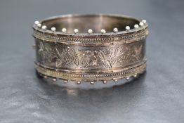 A Victorian silver hinged bangle having engraved foliate decoration with beaded border & concealed
