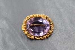 A yellow metal presumed gold amethyst set brooch, the central oval cut amethyst measuring