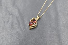 A 14ct gold garnet and diamond set pendant, the two heart cut garnets having a diamond accent within