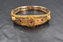 A 9ct gold garnet and diamond chip hinged bracelet, the central round cut garnet in a star cut