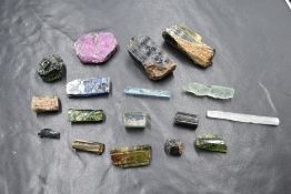 A collection of rough gemstones, including various colours of tourmaline, tabular ruby and selenite