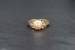 A yellow metal presumed gold pearl and diamond set ring, the central cultured pearl having a cream