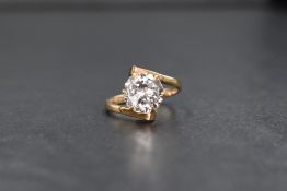 A yellow metal white sapphire solitaire ring, the claw set sapphire of approx 3ct with cross over