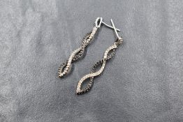 A pair of 10ct white gold diamond set earrings, the white and black diamonds in a spiral setting,
