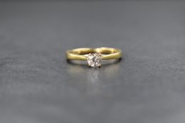 A yellow metal diamond set solitaire ring, the round brilliant cut diamond measuring approximately