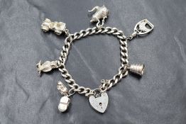 A silver charm bracelet having padlock clasp & six white metal charms including bootees, car etc,