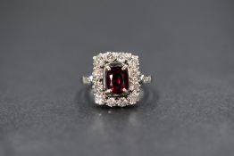 A platinum ruby and diamond set cluster ring, the central oval cut ruby measuring approximately 0.