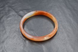 A carved banded agate bangle, having orange and white tones, 6cm internal diameter, 19.6g