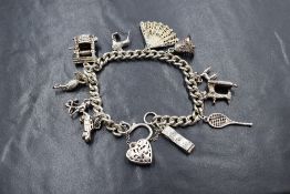 A white metal presumed silver, curb link charm bracelet, having a silver pierced heart padlock and