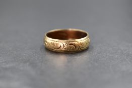 A 9ct gold band, having decorative scroll engraving, marked 375, ring size S-T, 4.7g
