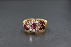An 18ct gold ruby & diamond cluster ring having a central ruby, approx 0.25ct, within a surround