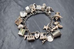 A silver double curb link charm bracelet, having a heart padlock clasp and twenty silver and white