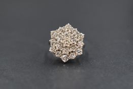 An 18ct white gold diamond set cluster ring, the nineteen round brilliant cut diamonds in a step