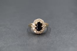 A 9ct gold sapphire and cubic zirconia set cluster ring, the central oval cut sapphire measuring