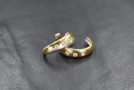 A pair of two tone 18ct gold diamond set hoop earrings, the three graduated round brilliant cut