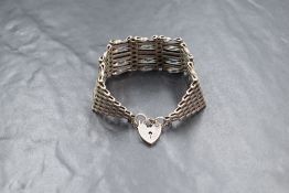 A silver eight bar gate bracelet of traditional form having a padlock clasp and safety chain, 25.6g