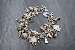 A silver curb link charm bracelet having a heart padlock clasp and approximately twenty-eight