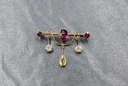 A yellow metal presumed gold garnet, peridot and cubic zirconia set bar brooch, the central oval cut