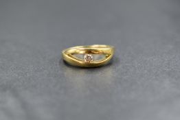 A yellow metal diamond solitaire ring having a 0.125ct brilliant cut diamond in a bezel mount to