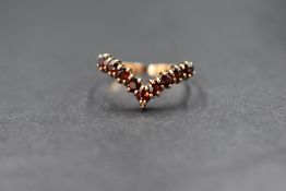 A 9ct gold garnet set wishbone ring, the nine round cut garnets in a wishbone setting, marked 375,