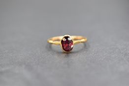 An 18ct gold garnet set ring, the oval cut garnet in a bezel setting, marked 18ct with hallmarks,