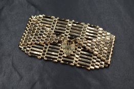 A 9ct gold fourteen bar graduated gate bracelet, having a heart padlock and safety chain, marked
